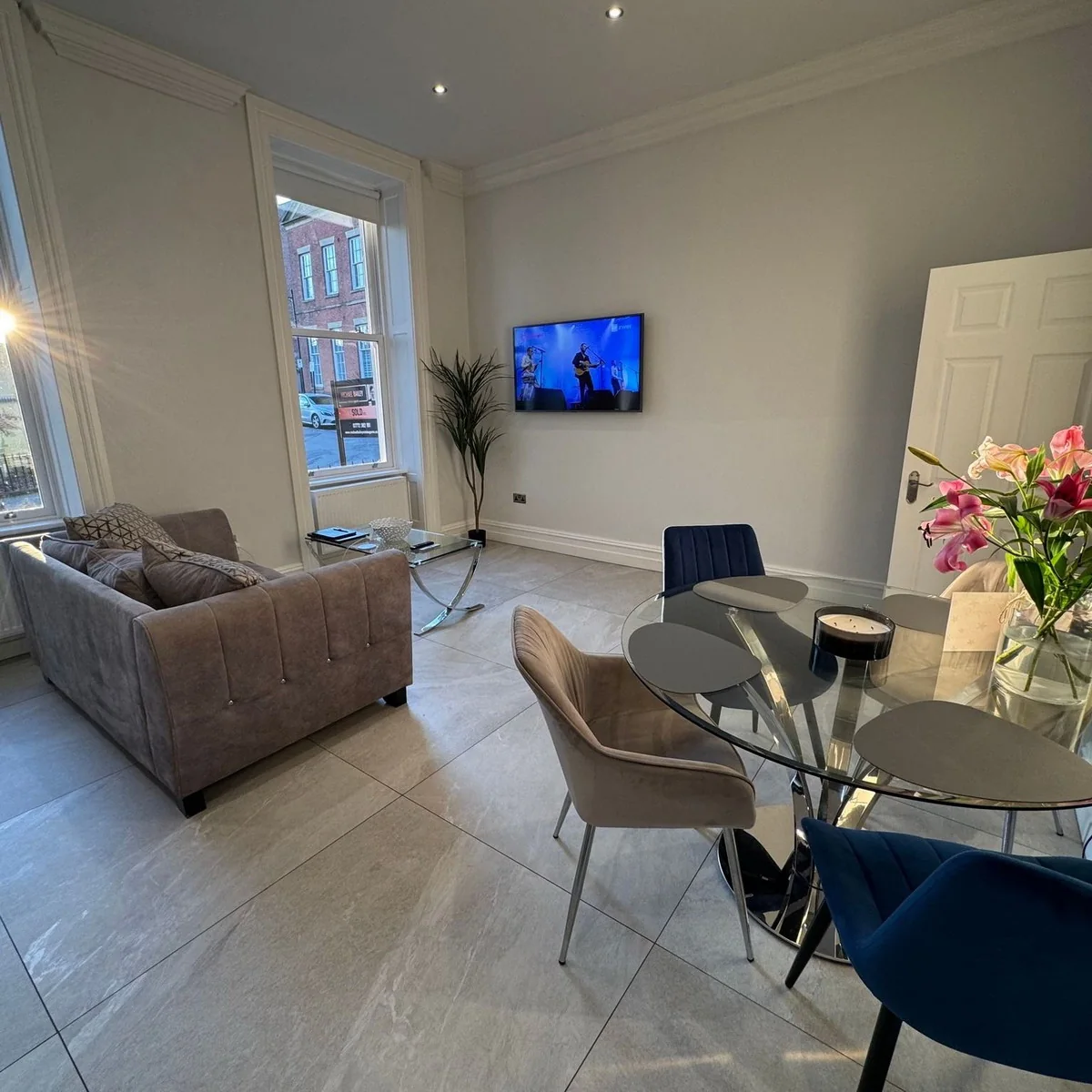 Open-plan living and dining area with sofa, smart TV and glass dining table
