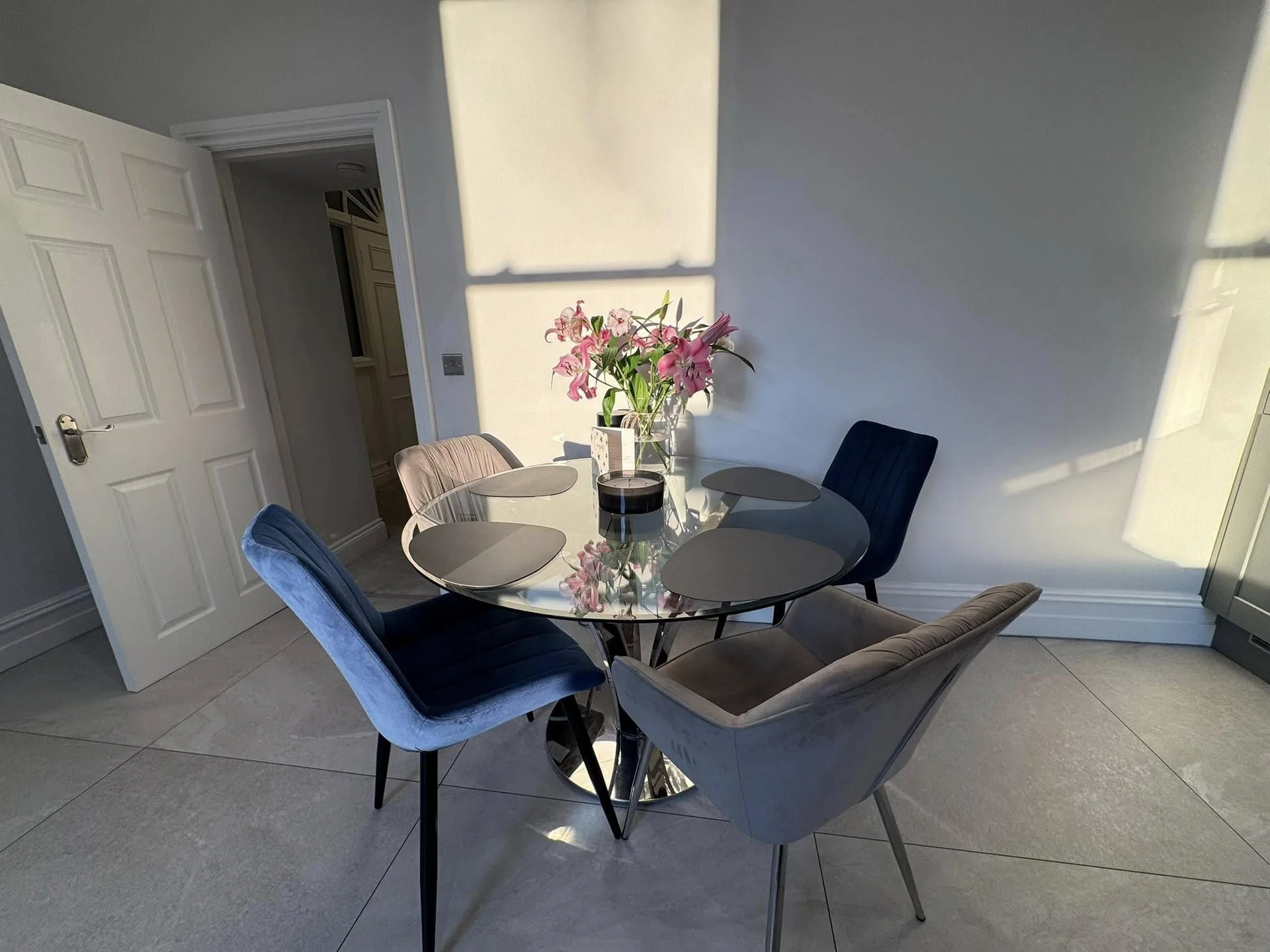 Round glass dining table with velvet chairs and fresh flowers