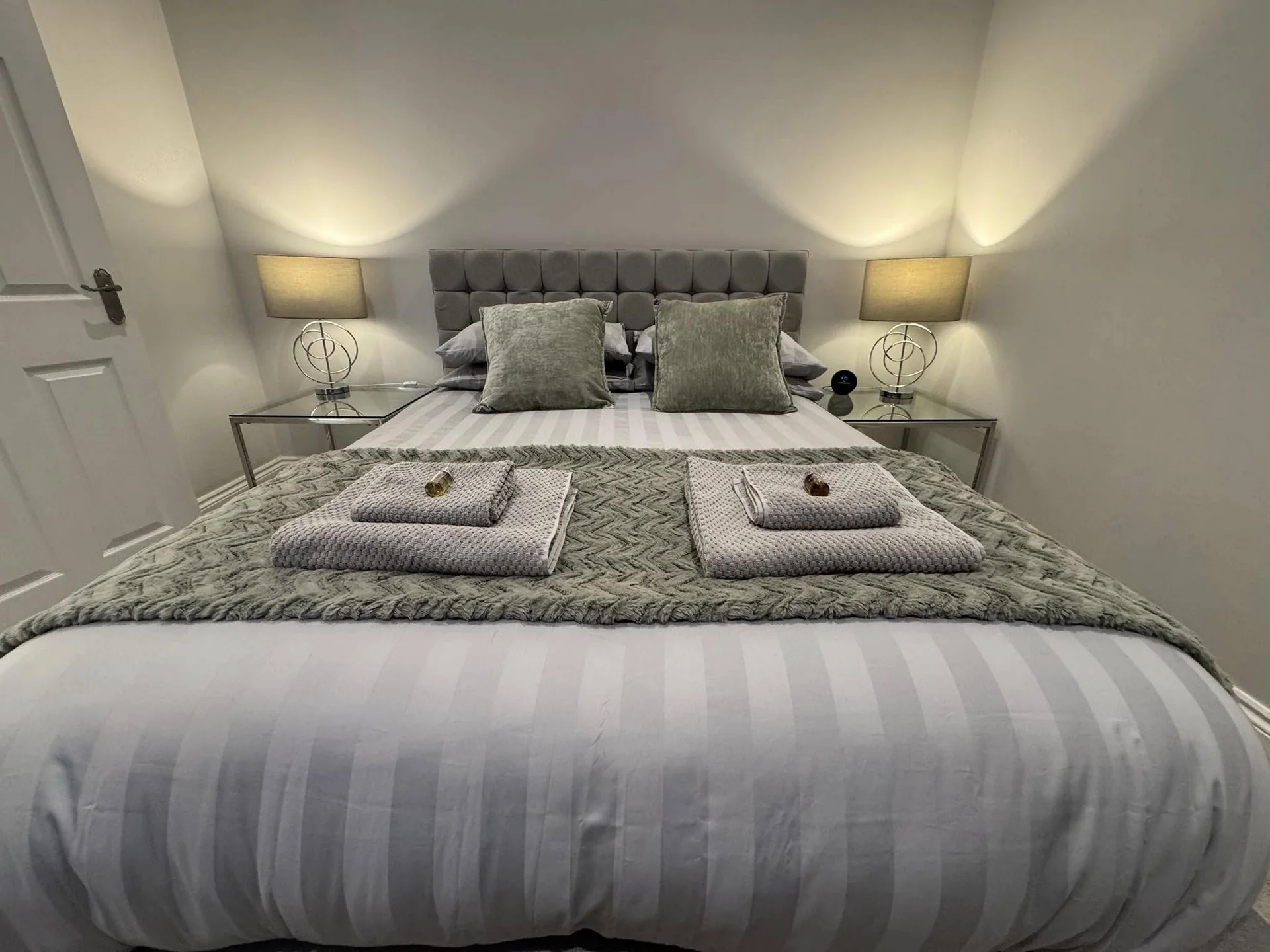 King-size bed with grey upholstered headboard and bedside lamps