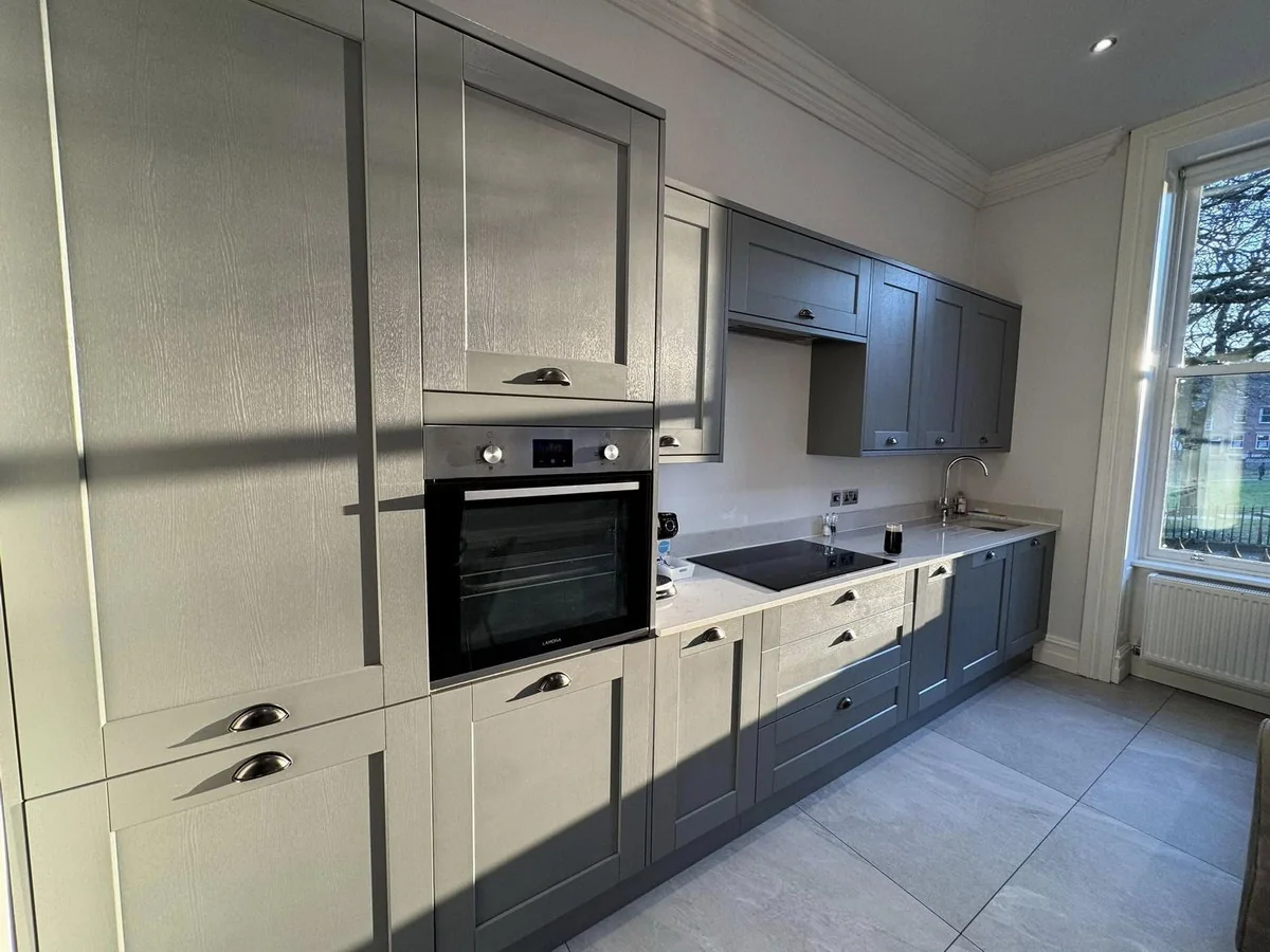 Fully equipped modern kitchen with grey units, oven and hob